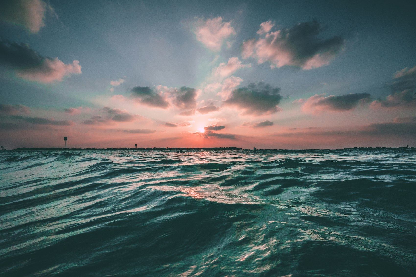 Vagues de l'océan au lever du soleil, rayons de lumière à travers les nuages à l'horizon, illustration de l'horizon long terme de l'épargne retraite avec un PER